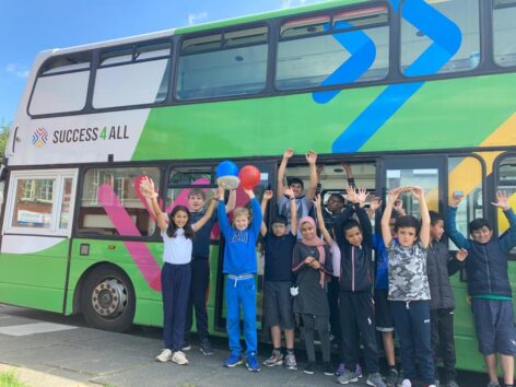 Summer school children standing by a double decker bus